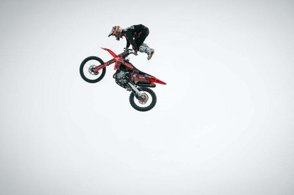 man in mid air on a red dirt bike