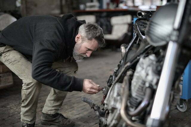 male mechanic examining motorcycle in workshop