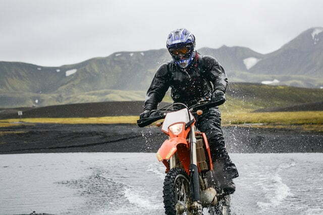 man riding dirt bike in shallow river