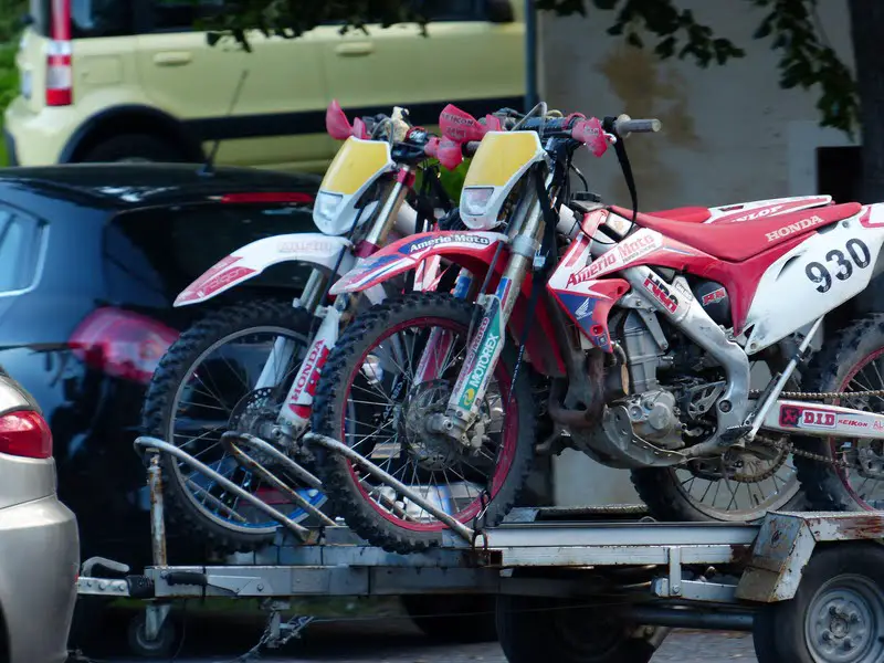 two dirt bikes on trailer towed by car