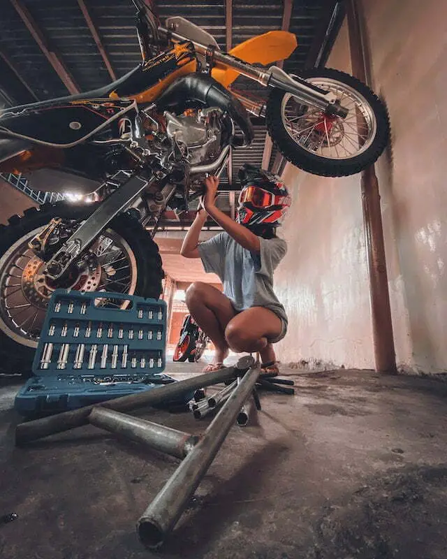 young woman repairing dirt bike in garage