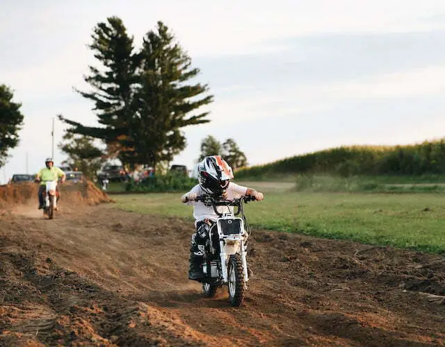 child riding motorcycle on dirt road during daytime