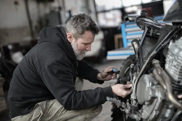 man-fixing-dirt-bike-in-garage